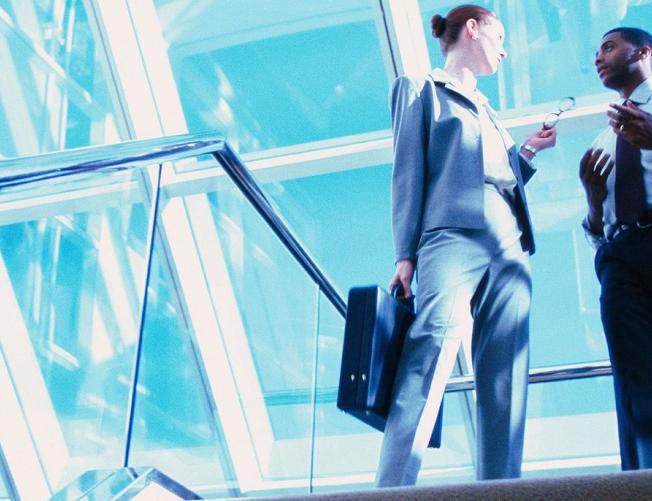 professional woman and man talking at the top of a staircase