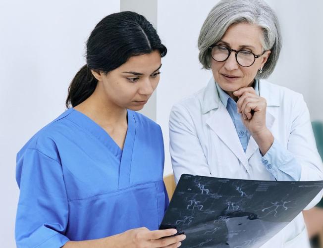 Female doctor looking at scans with a younger intern in a ho
