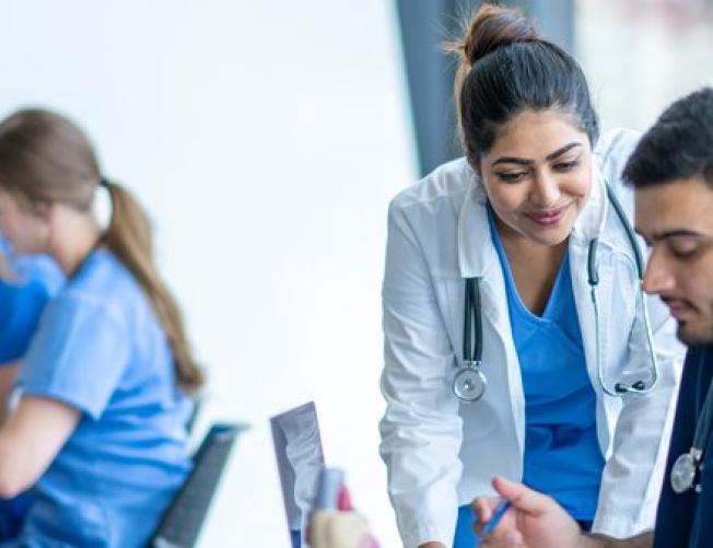 Teacher helping students in a medical school classroom