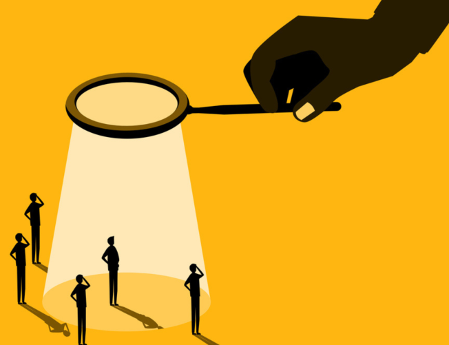 Magnifying glass shining down on five figures. 