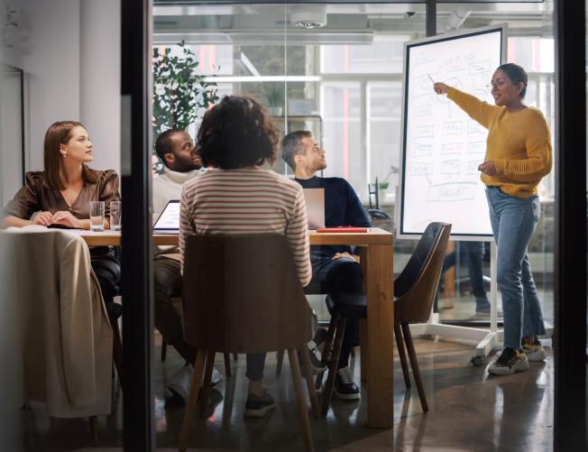 Project Manager Makes a Presentation for a Young Diverse Creative Team in Meeting Room in an Agency.