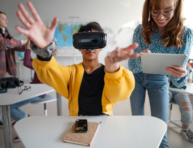 Teenage students wearing virtual reality goggles at school in a computer science class