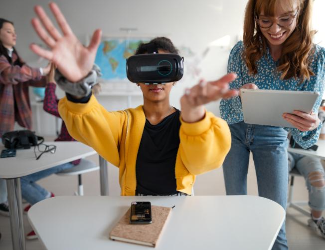 Teenage students wearing virtual reality goggles at school in a computer science class