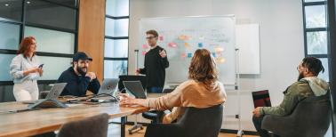 Diverse colleagues collaborating in a modern boardroom, working on projects and discussing ideas as a tech team