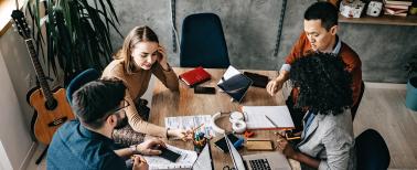 High angle view of multi-ethnic group of coworkers collaborating on a project with their laptops and data sheets