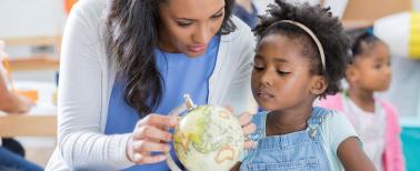 teacher showing young child a globe of the world