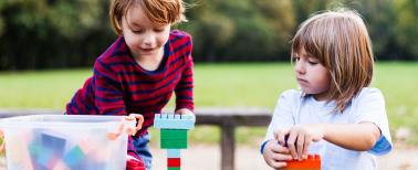 two young children outside playing with Legos