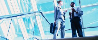 professional woman and man talking at the top of a staircase