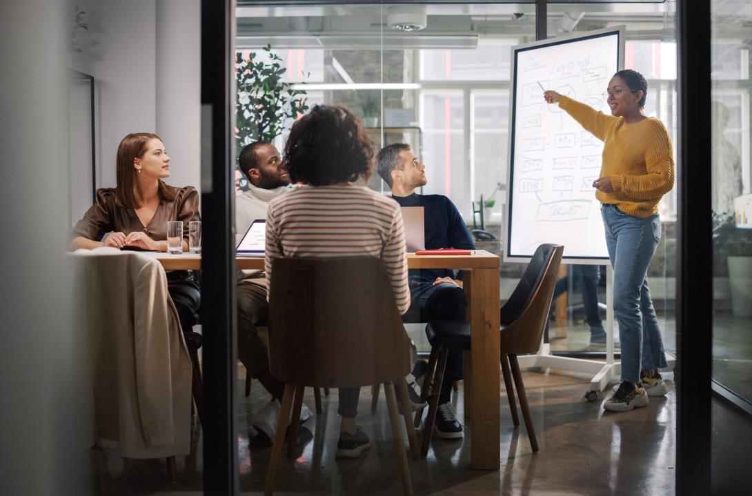 Project Manager Makes a Presentation for a Young Diverse Creative Team in Meeting Room in an Agency.