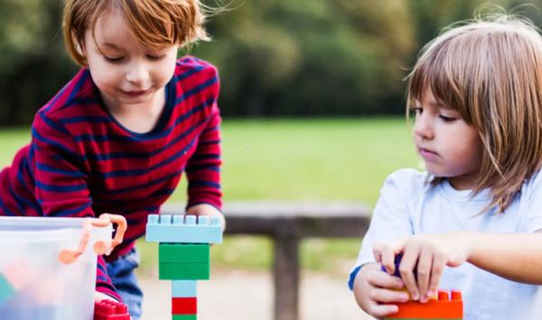 Two pre-school -age children playing with toys outside