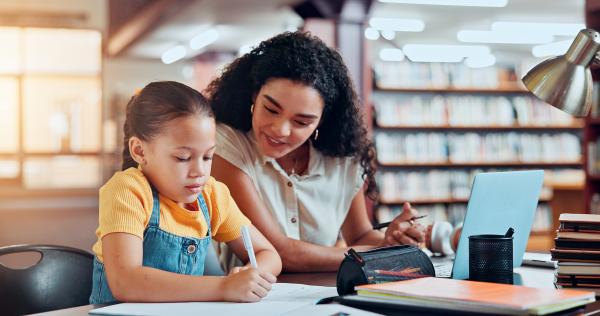 teacher and pre-school student writing in a classroom