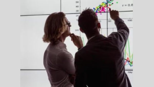 Two people looking at a chart on a screen.
