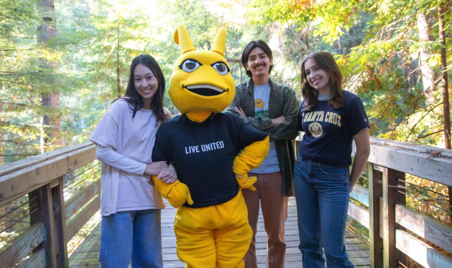 UCSC Mascot Sammy with three UCSC students on a wooden bridge